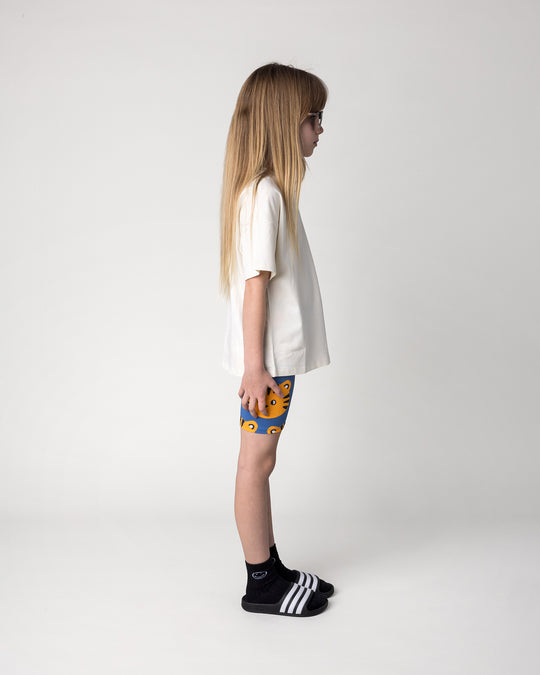 Kid wearing the Hello Tiger Bike Pant in blue with the Hello Tiger Tee in cream, side view