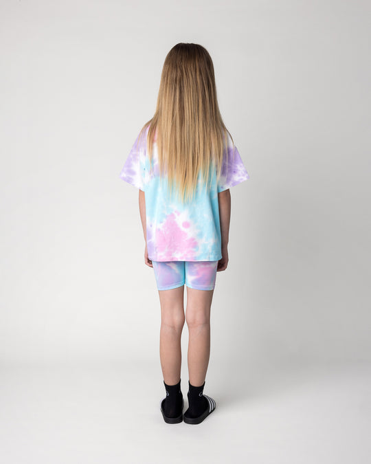 Kid wearing the Tie Dye Bike Pant in multi with the Pocket Flower Tee in tie dye, back view