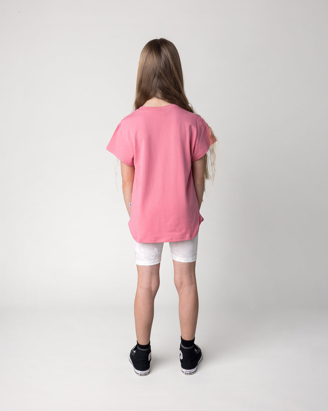 Kid wearing the Velvet Bike Pant in cream with the Icecream Bunny Tee in candy, back view