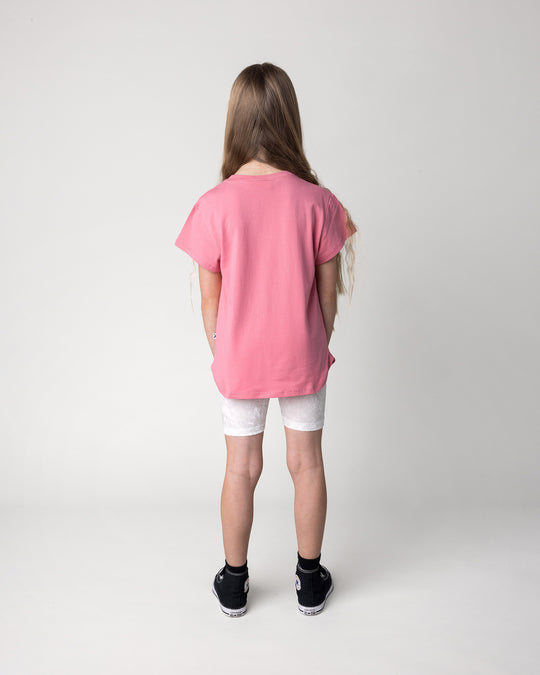 Kid wearing the Velvet Bike Pant in cream with the Icecream Bunny Tee in candy, back view