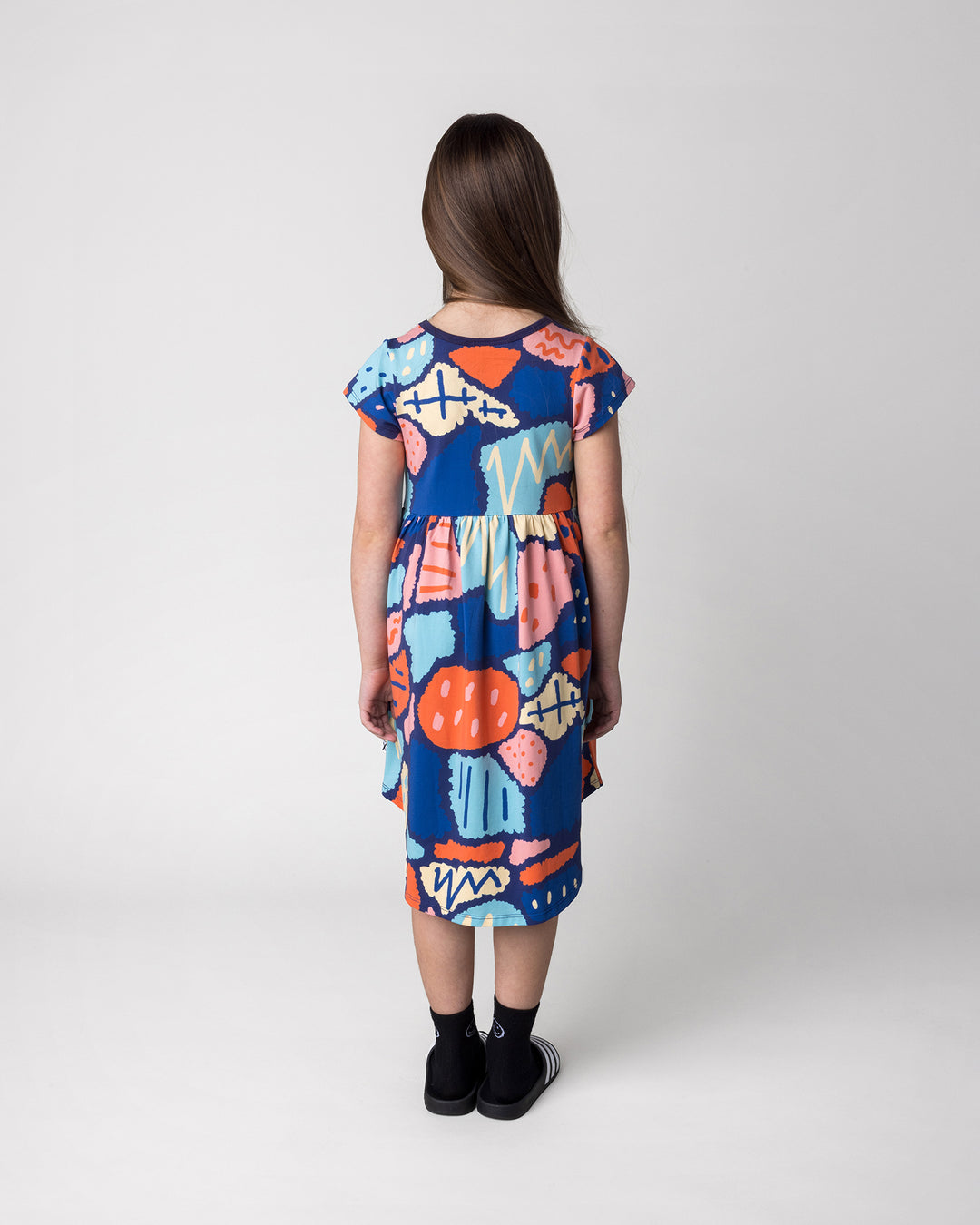 Kid wearing the Cool Shapes Dress in dark blue, back view