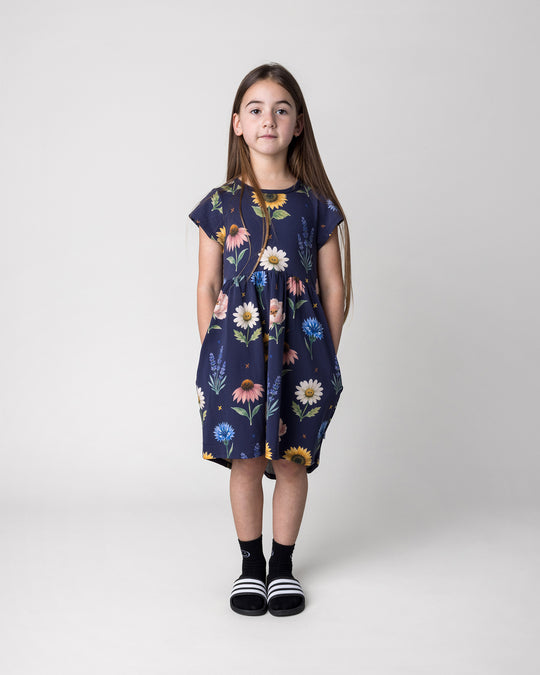 Kid wearing the Flower Friends Dress in ink, front view