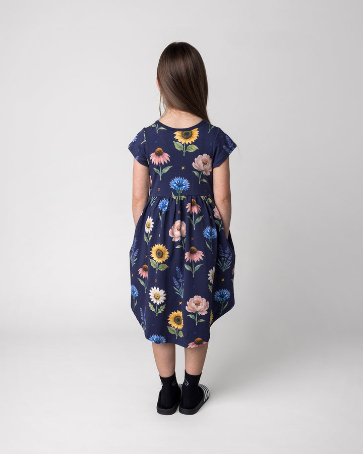 Kid wearing the Flower Friends Dress in ink, back view