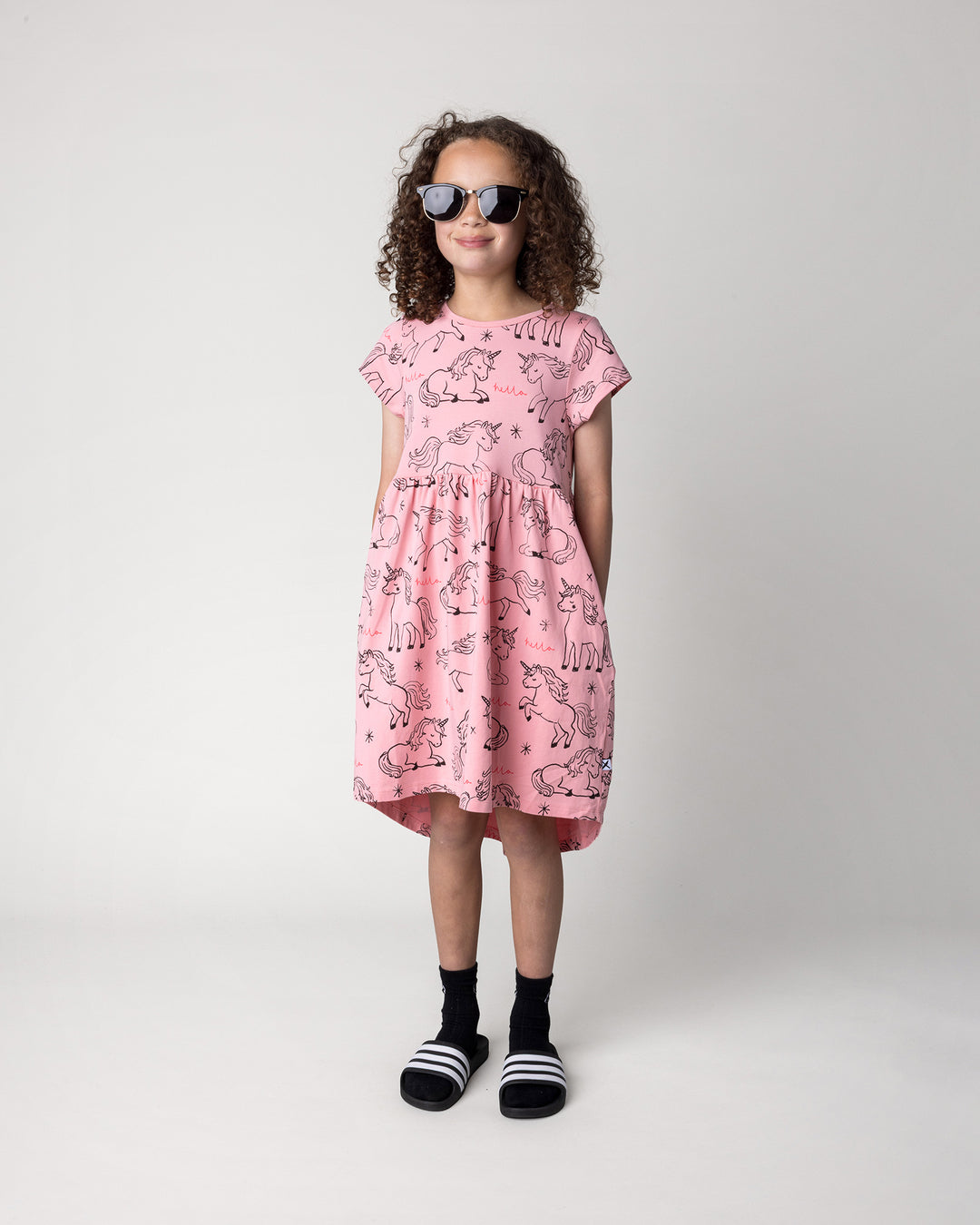 Kid wearing the Hello Unicorns Dress in pink, front view