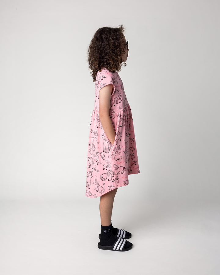 Kid wearing the Hello Unicorns Dress in pink, side view