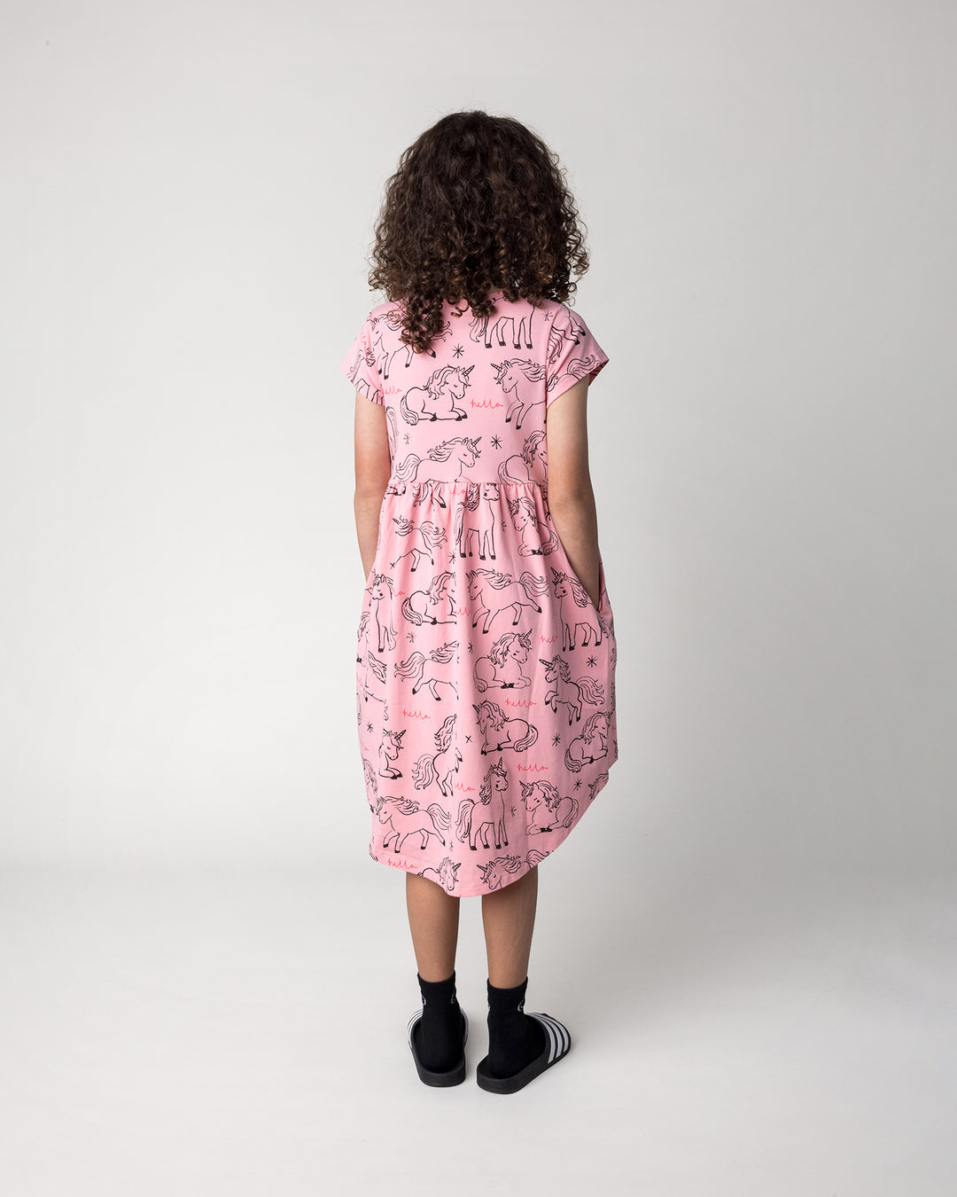Kid wearing the Hello Unicorns Dress in pink, back view