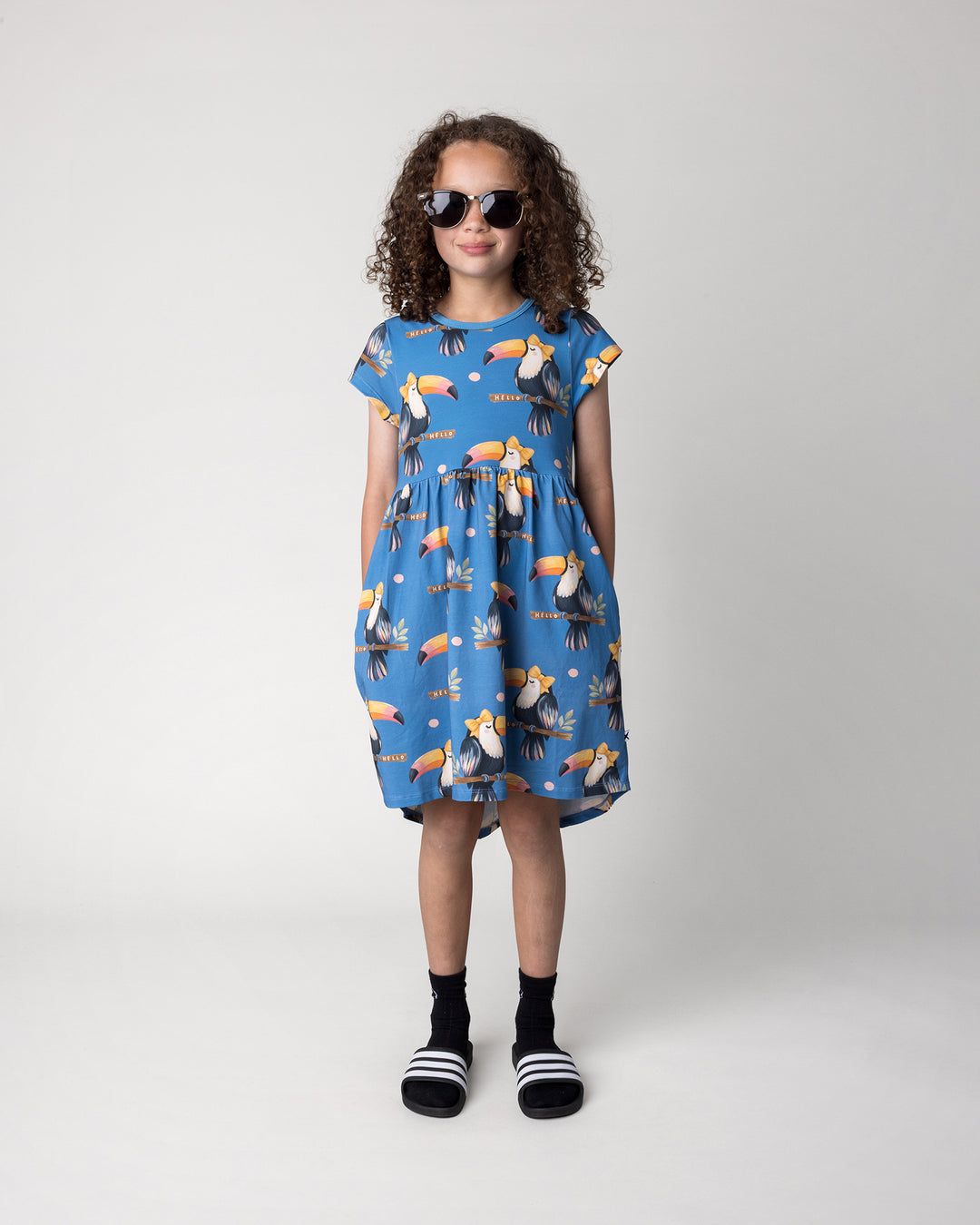 Kid wearing the Hello Toucan Dress in aqua, front view
