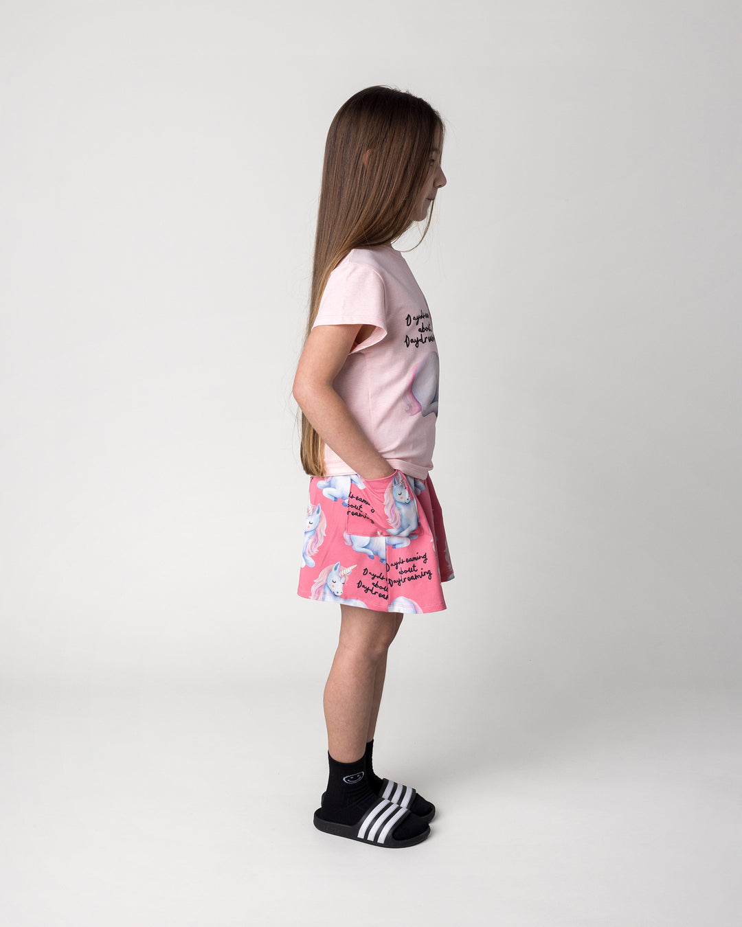 Kid wearing the Daydreaming Unicorn Skirt in candy with the Daydreaming Unicorn Tee in pink marle, side view