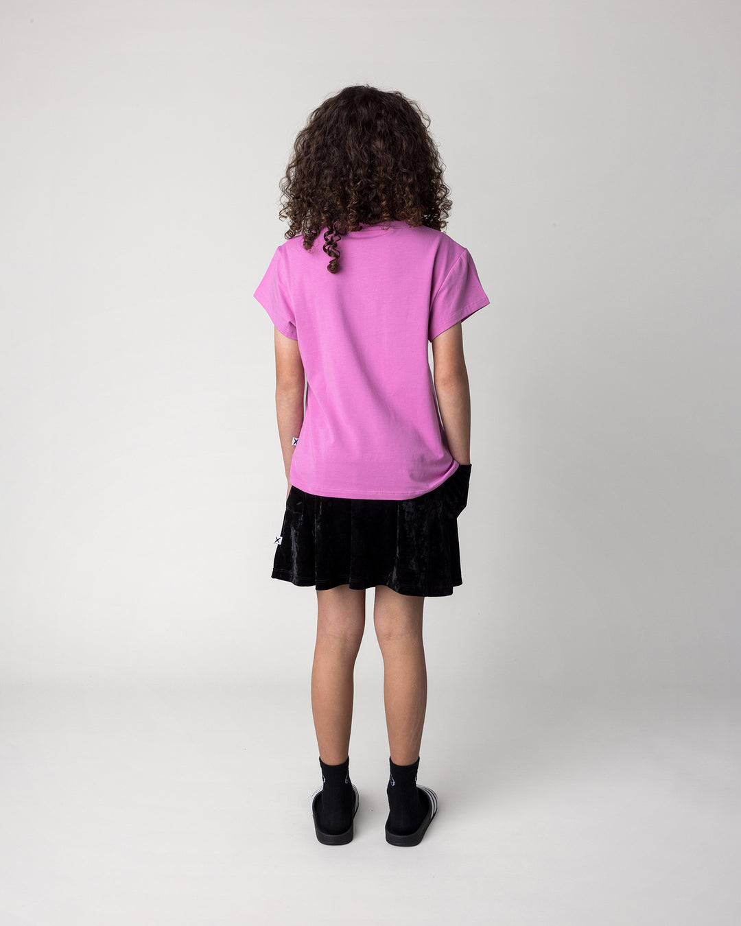 Kid wearing the Velvet Skirt in black with the Stay Cool Tee in violet, back view