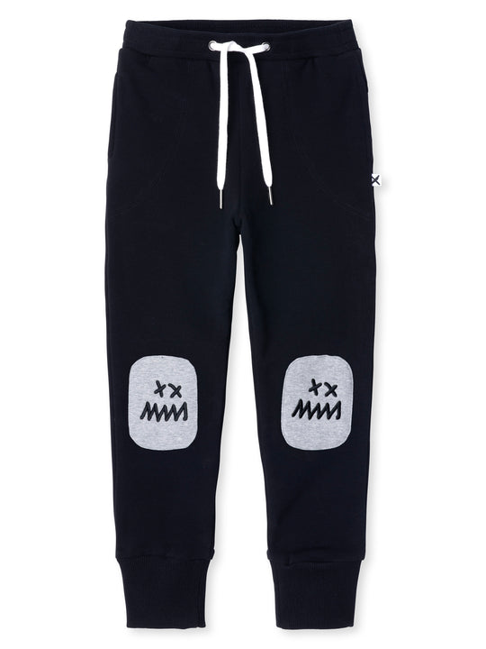 Minti kids clothing. Luxe trackies with sewn on patch knees, front pockets and shoelace ties. Super cool embroideries on the knee patches. 330 Gram // Brushed Inside // 95% Cotton // 5% Elastane.