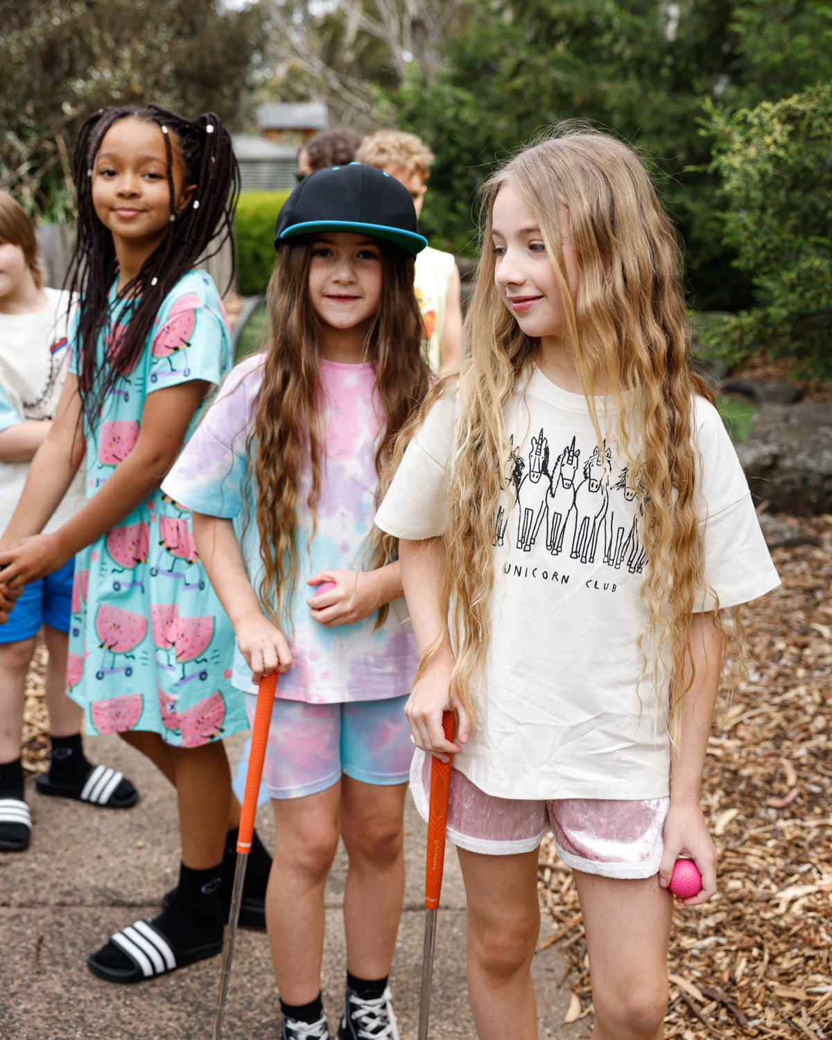 Kids in the Minti Scooting Watermelon dress and Unicorn Club tee at mini golf