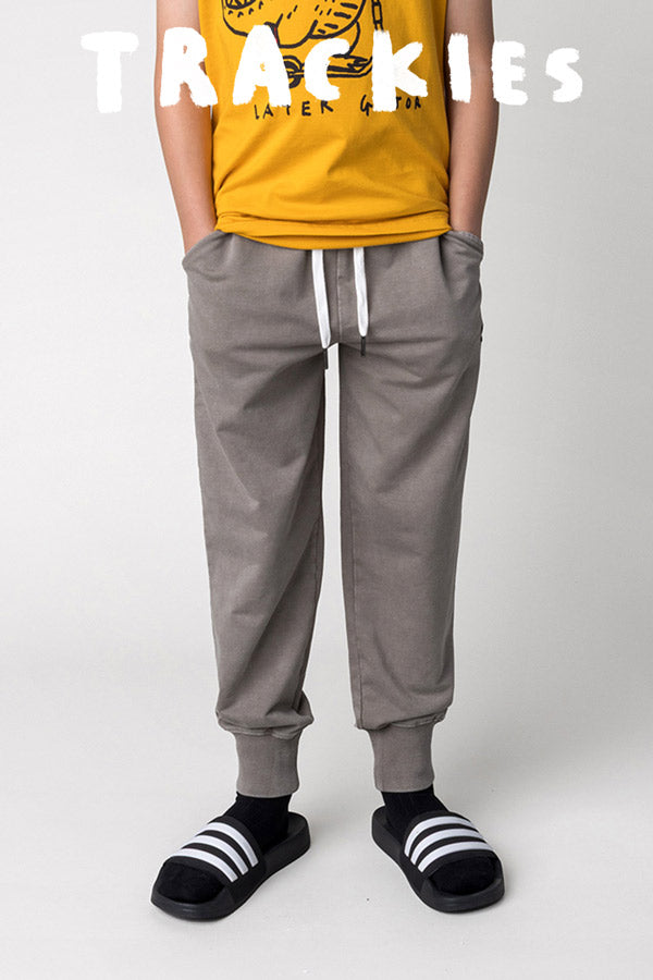 Shop trackies at Minti, kid wearing the Blasted Studio Trackies in grey wash