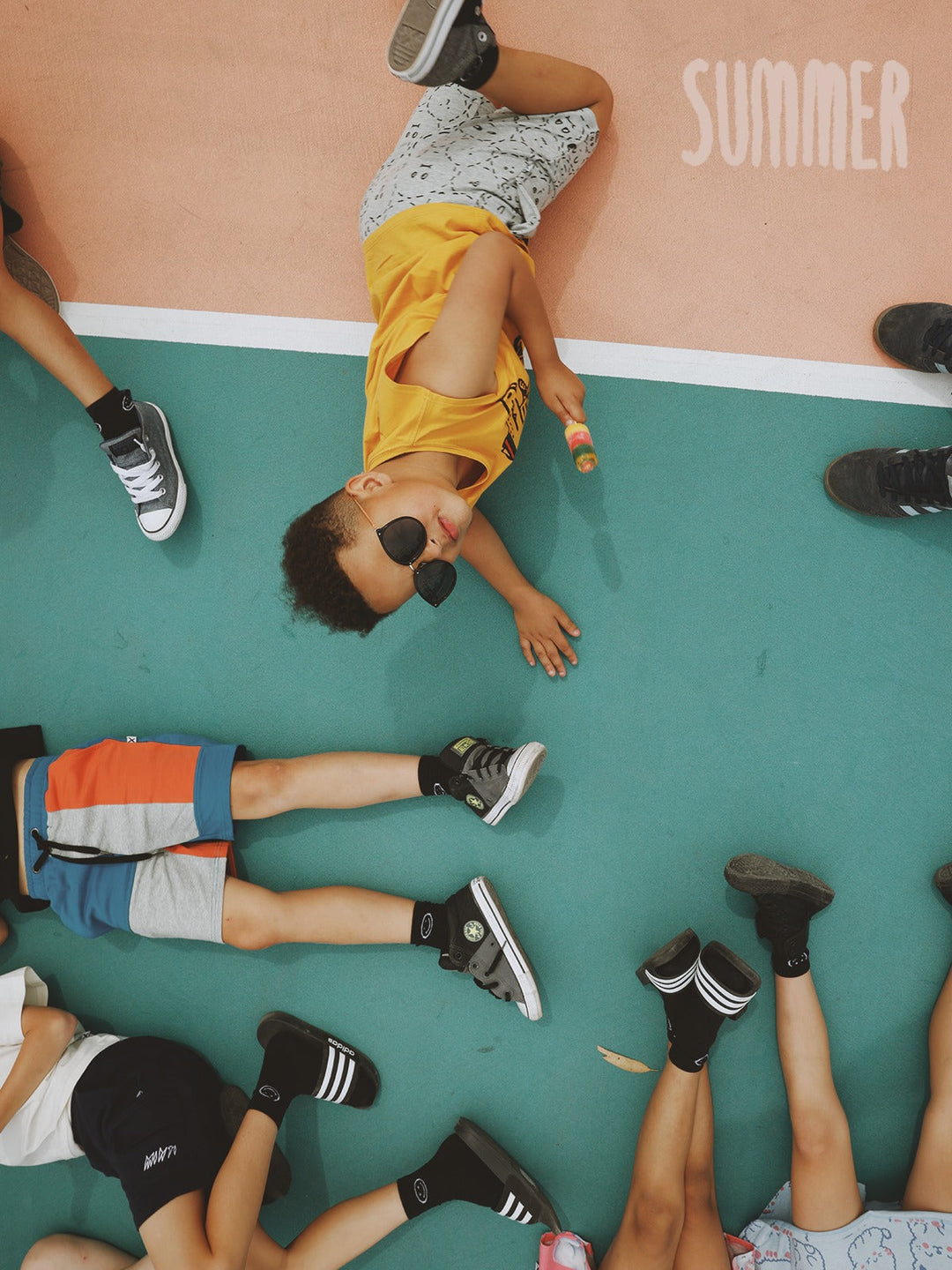 Kids lying on a court with ice blocks, wearing Minti summer tees and shorts
